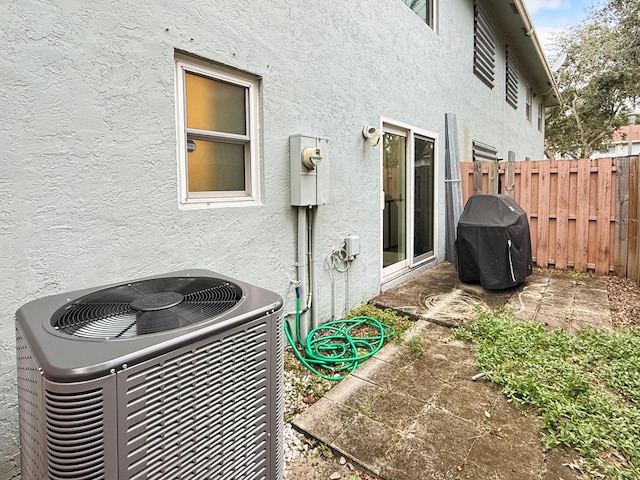 exterior details featuring central AC unit, electric meter, fence, and stucco siding