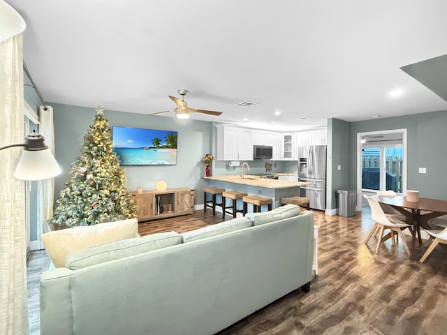 living room featuring visible vents, a ceiling fan, baseboards, and dark wood-style flooring