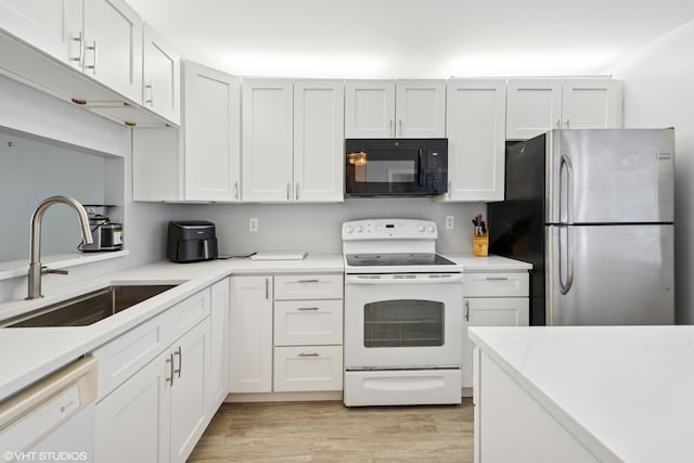 kitchen with light countertops, light wood-style flooring, white cabinets, a sink, and white appliances