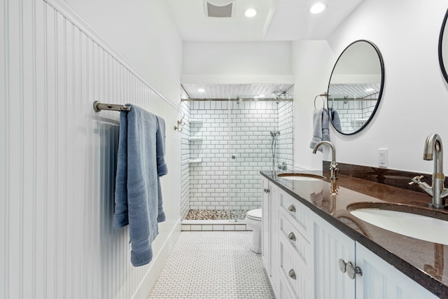 full bath with double vanity, a stall shower, a sink, and toilet