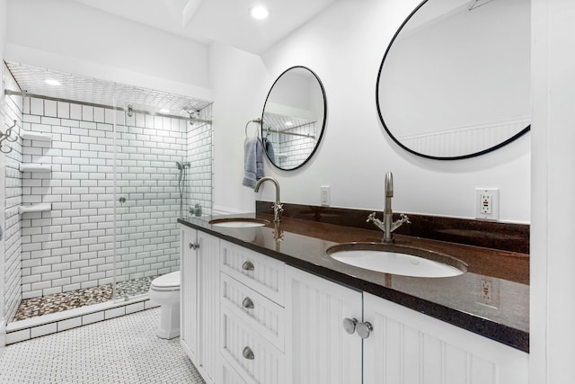 bathroom featuring double vanity, a stall shower, a sink, and toilet