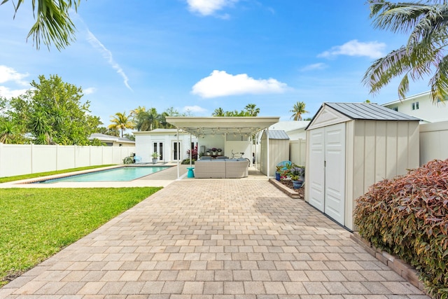 view of pool with an outbuilding, a patio, a fenced backyard, a storage shed, and a yard