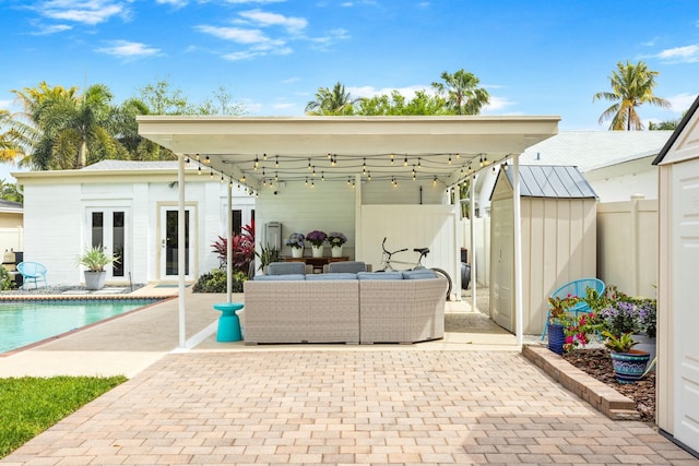 view of patio / terrace with an outbuilding, french doors, outdoor lounge area, fence, and an outdoor pool