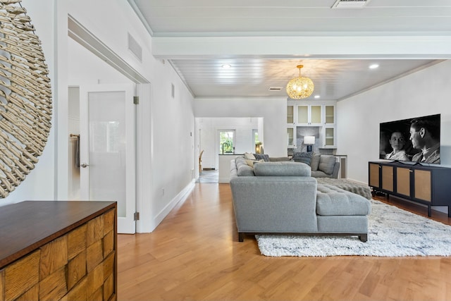 living area featuring baseboards, light wood-type flooring, visible vents, and an inviting chandelier