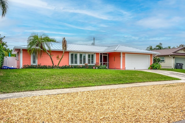 ranch-style home featuring driveway, a garage, a front lawn, and metal roof