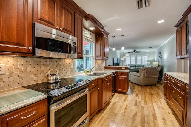 kitchen with stainless steel appliances, a sink, visible vents, open floor plan, and light wood finished floors