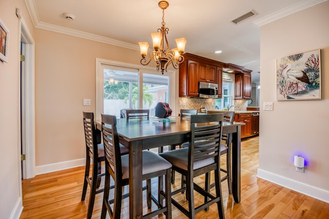 dining area with ornamental molding, visible vents, light wood-style flooring, and baseboards