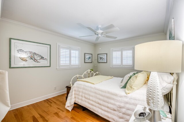 bedroom featuring ornamental molding, multiple windows, baseboards, and wood finished floors