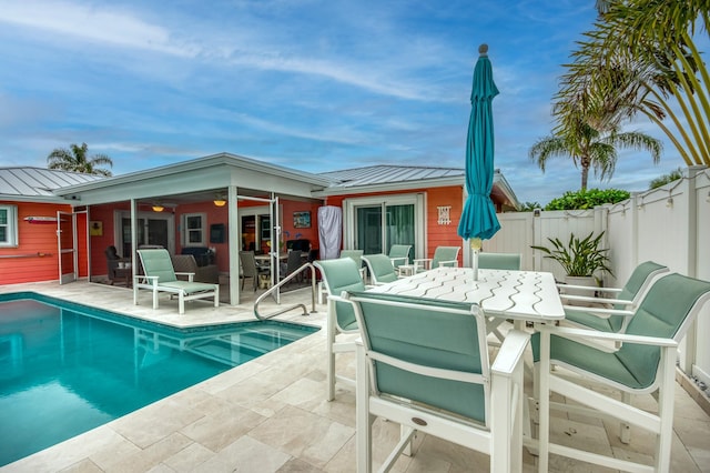 back of property with a standing seam roof, outdoor dining space, metal roof, and a patio