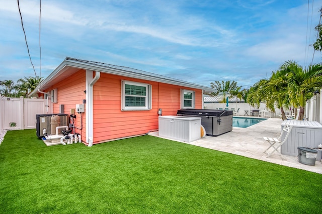 rear view of property featuring a yard, a hot tub, a fenced backyard, and a patio