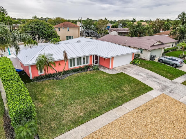 single story home with an attached garage, metal roof, concrete driveway, and a front yard