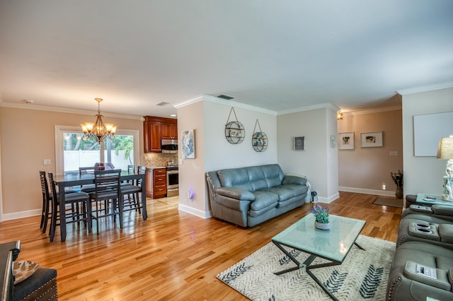 living room with light wood finished floors, baseboards, visible vents, crown molding, and a chandelier