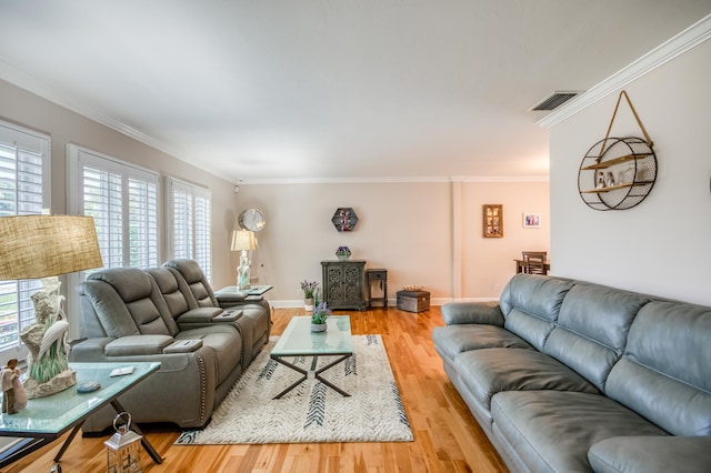 living room featuring baseboards, ornamental molding, visible vents, and light wood-style floors