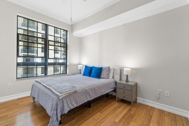 bedroom with ornamental molding, baseboards, and wood finished floors