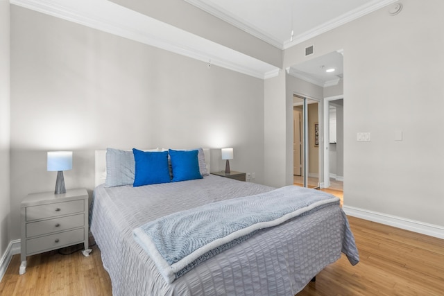 bedroom with baseboards, visible vents, wood finished floors, and ornamental molding