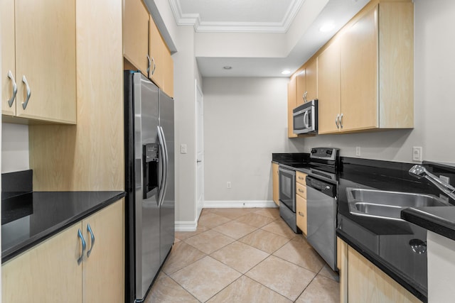 kitchen featuring dark countertops, appliances with stainless steel finishes, a sink, and light brown cabinetry