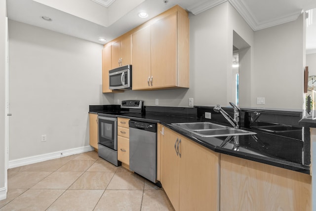 kitchen featuring dark countertops, stainless steel appliances, crown molding, light brown cabinets, and a sink