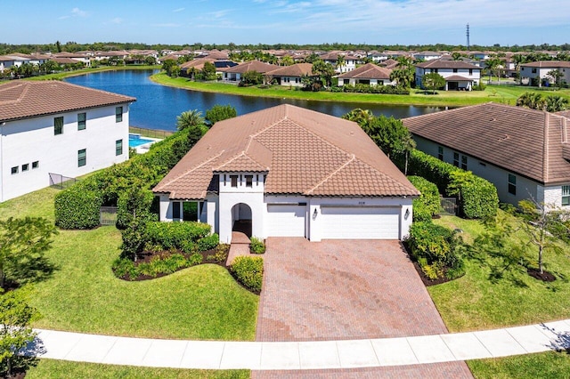 view of front of home featuring an attached garage, a front lawn, a tiled roof, decorative driveway, and a residential view