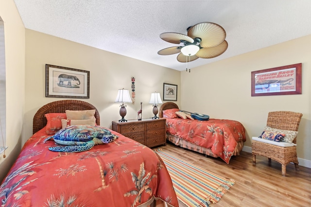 bedroom featuring baseboards, a textured ceiling, wood finished floors, and a ceiling fan