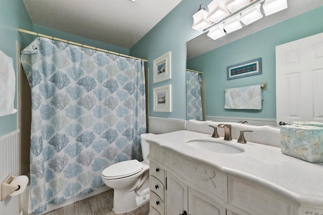 full bathroom featuring vanity, a shower with shower curtain, wood finished floors, wainscoting, and toilet