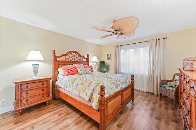 bedroom featuring a textured ceiling, baseboards, light wood-type flooring, and a ceiling fan