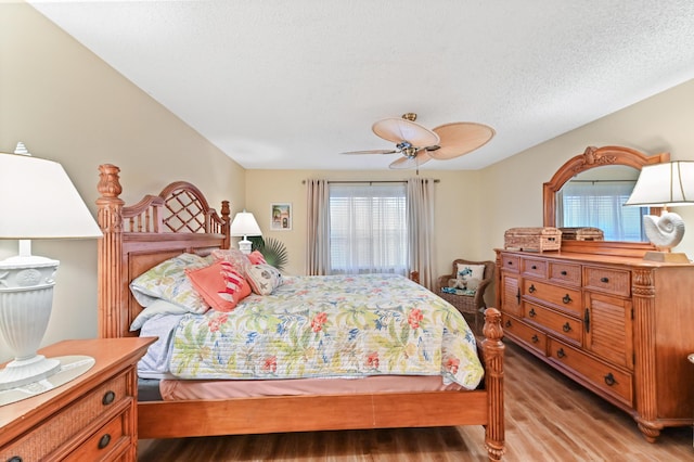 bedroom with a textured ceiling, light wood-style flooring, and a ceiling fan