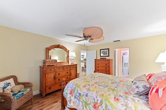 bedroom with visible vents, baseboards, wood finished floors, a textured ceiling, and a ceiling fan