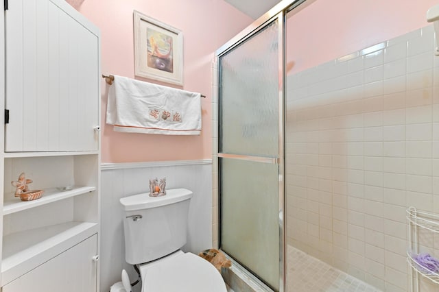 bathroom featuring wainscoting, a stall shower, and toilet