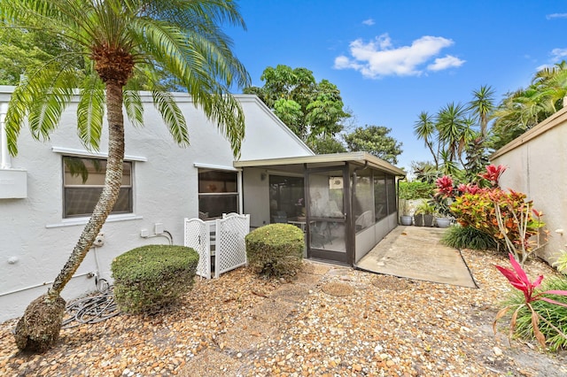 back of property featuring stucco siding, a patio area, and a sunroom