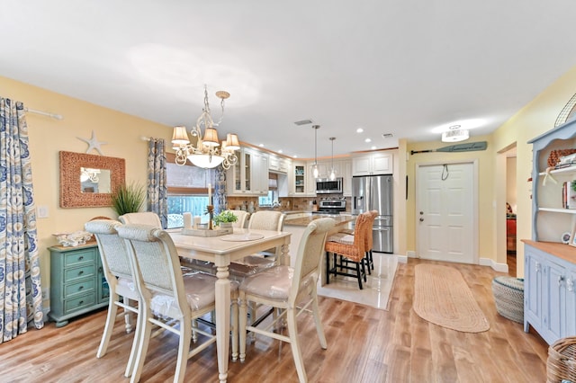 dining space with a notable chandelier, recessed lighting, light wood-type flooring, and baseboards