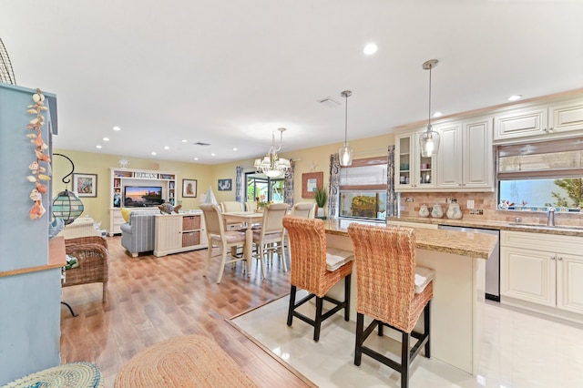 kitchen featuring a fireplace, a sink, stainless steel dishwasher, backsplash, and a center island