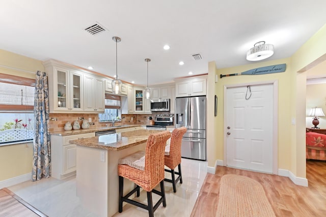 kitchen featuring a sink, a center island, appliances with stainless steel finishes, a breakfast bar area, and decorative backsplash