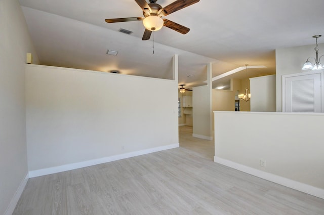 unfurnished room featuring lofted ceiling, light wood-style flooring, ceiling fan with notable chandelier, visible vents, and baseboards