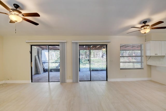 unfurnished living room featuring light wood-type flooring, a ceiling fan, and baseboards