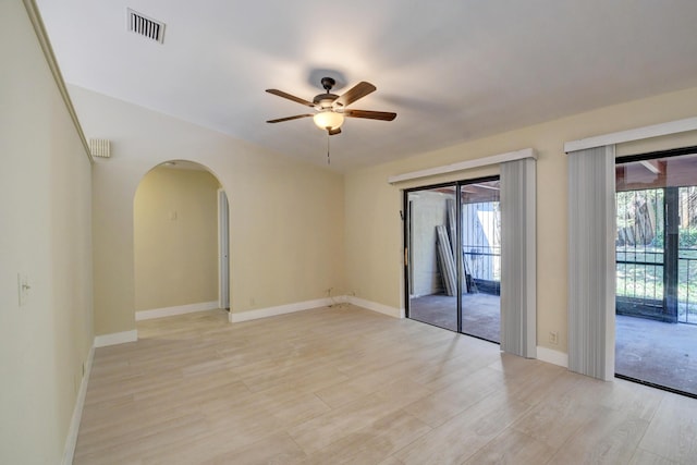 spare room featuring a healthy amount of sunlight, ceiling fan, visible vents, and arched walkways