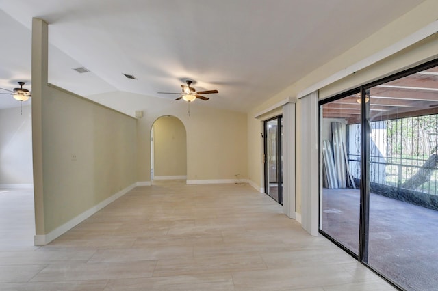 unfurnished room featuring arched walkways, ceiling fan, visible vents, and baseboards