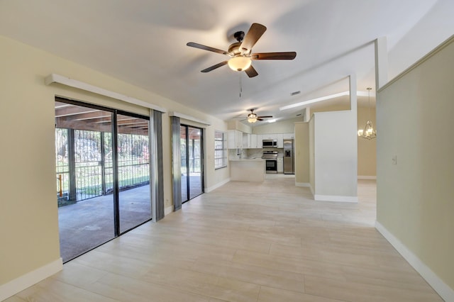 unfurnished living room with lofted ceiling, visible vents, baseboards, and ceiling fan with notable chandelier