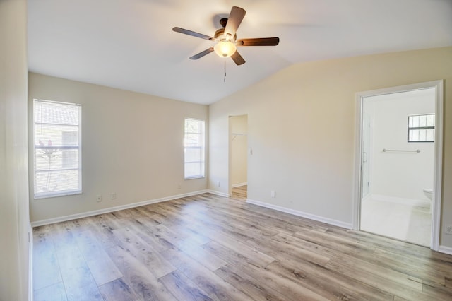 spare room featuring vaulted ceiling, ceiling fan, baseboards, and light wood-style floors