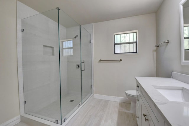 full bathroom featuring a stall shower, toilet, vanity, and baseboards