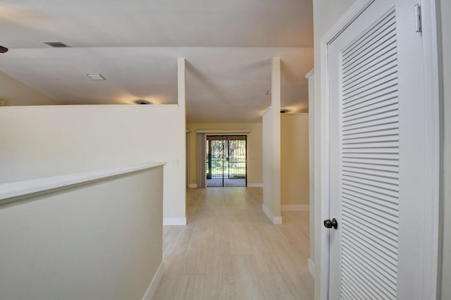 corridor with light wood-type flooring, baseboards, and visible vents