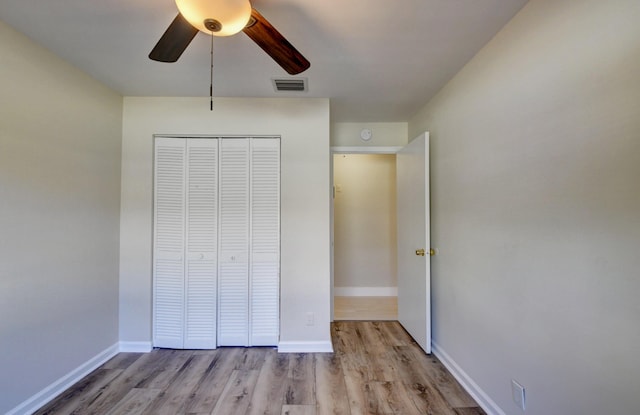 unfurnished bedroom with a closet, visible vents, a ceiling fan, wood finished floors, and baseboards