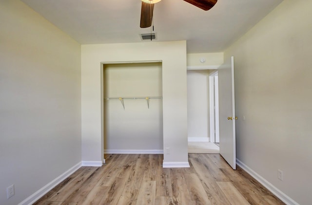 unfurnished bedroom with a closet, visible vents, a ceiling fan, wood finished floors, and baseboards