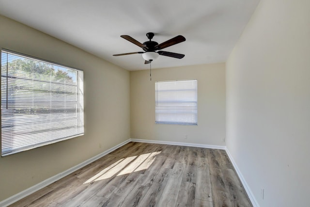 empty room with ceiling fan, baseboards, and wood finished floors