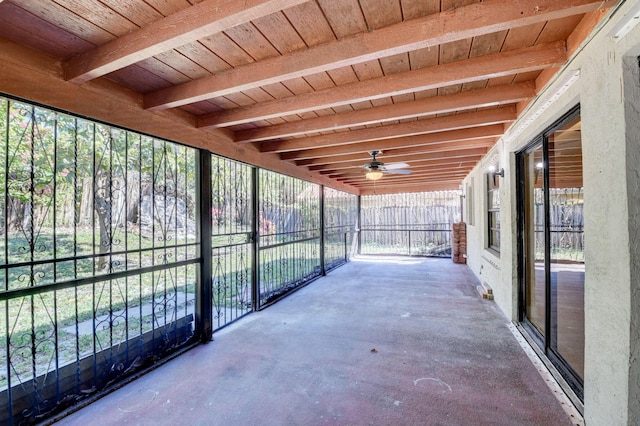 unfurnished sunroom with a ceiling fan and beamed ceiling