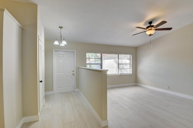 foyer with light wood-type flooring, baseboards, and ceiling fan with notable chandelier