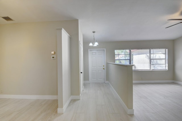 foyer featuring light wood-style floors, visible vents, baseboards, and ceiling fan with notable chandelier