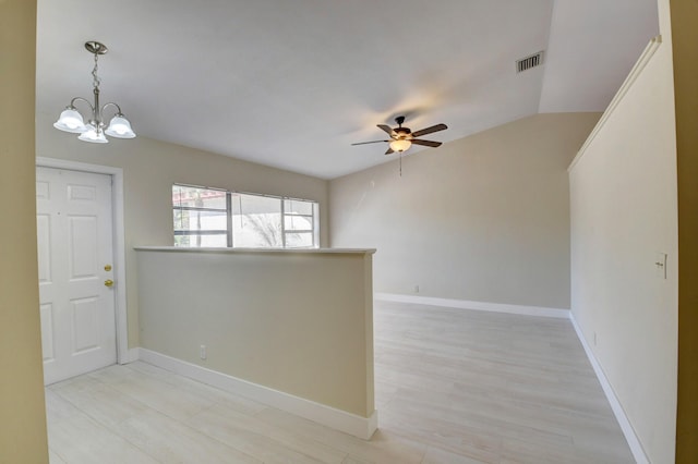 empty room featuring lofted ceiling, baseboards, visible vents, and ceiling fan with notable chandelier