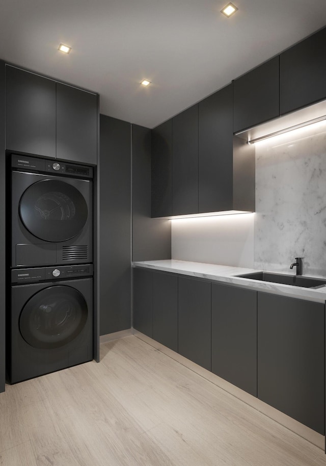 clothes washing area featuring light wood-style floors, a sink, cabinet space, and stacked washer / drying machine