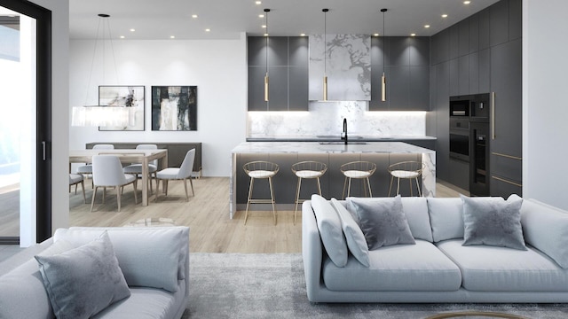 kitchen with light wood-type flooring, modern cabinets, a kitchen island with sink, and decorative backsplash