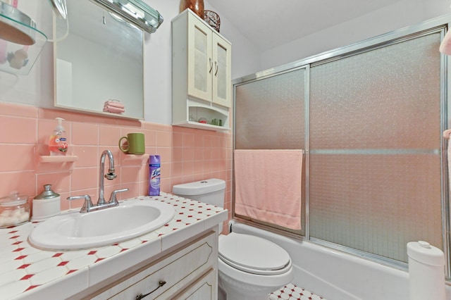 bathroom featuring vanity, tile walls, toilet, and enclosed tub / shower combo